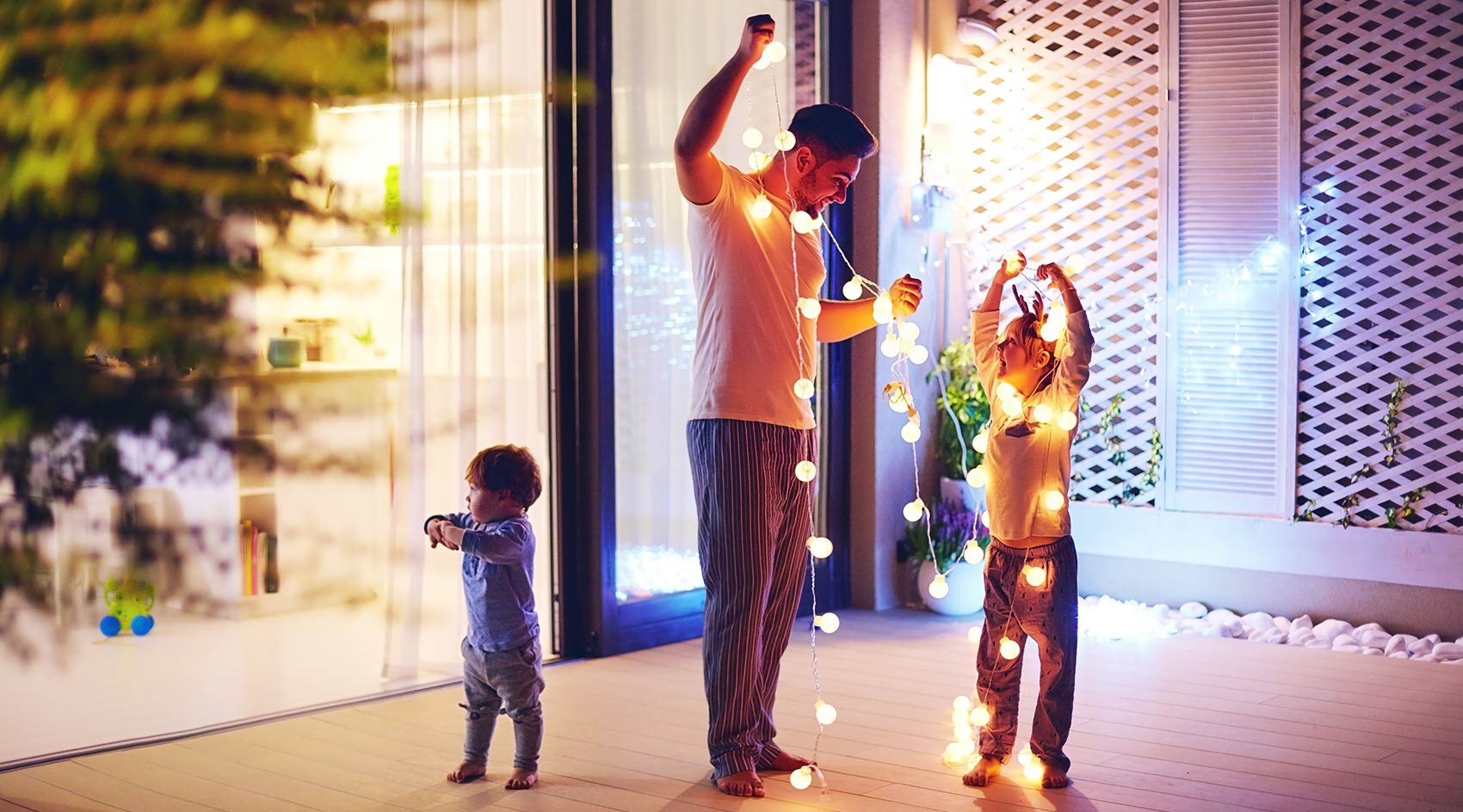 Dad reviews electrical safety tips with kids while hanging light strands