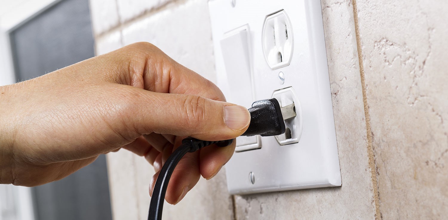 plugging in an electrical cord into an electrical outlet