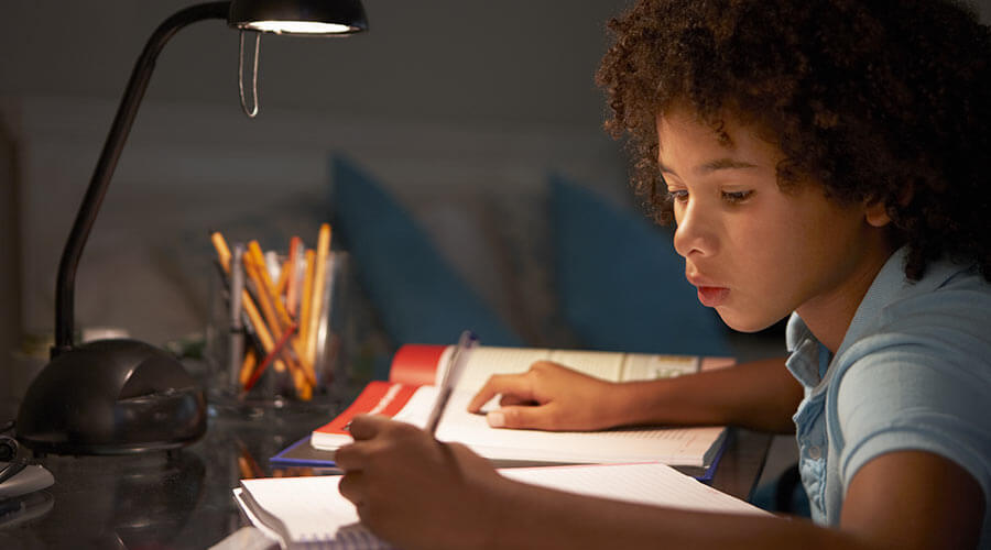 Child doing homework by lamplight 