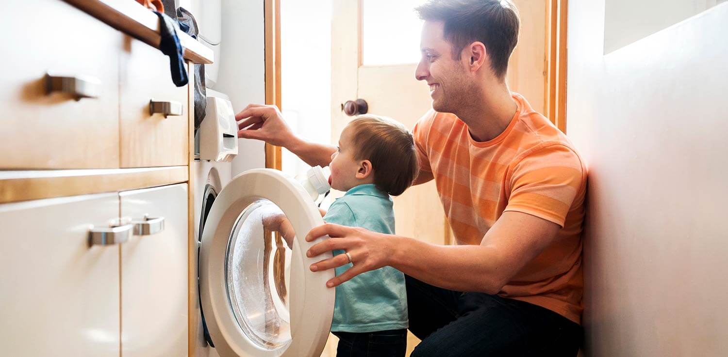 Father and child loading a clothes dryer.